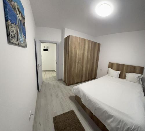 - une chambre avec un lit blanc et une porte en bois dans l'établissement Nova Residence Leordeni, à Popeşti-Leordeni