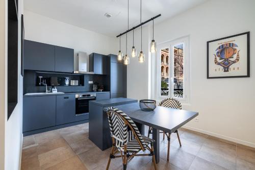 une cuisine avec des armoires bleues et une table et des chaises dans l'établissement Le Laurenti, vue mer époustouflante, à Menton