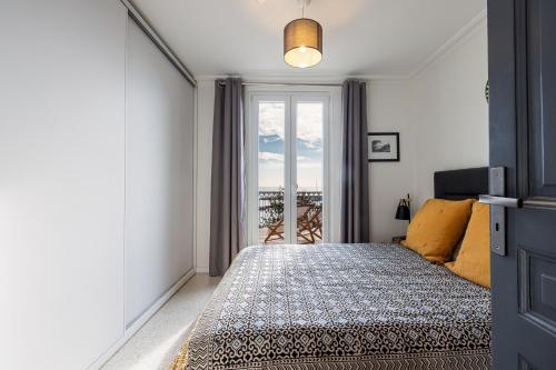 une chambre avec un lit et une grande fenêtre dans l'établissement Le Laurenti, vue mer époustouflante, à Menton