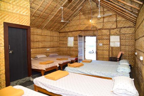 a room with four beds in a straw building at Sunny Guest House Hampi in Hampi