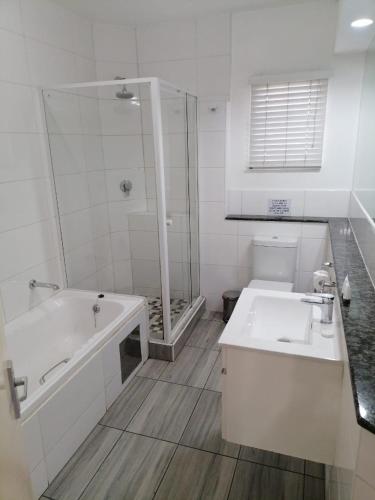 a white bathroom with a tub and a sink at Airport Inn and Suites in Johannesburg