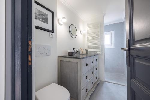 La salle de bains est pourvue d'un lavabo et d'une commode avec un miroir. dans l'établissement Le Laurenti, vue mer époustouflante, à Menton