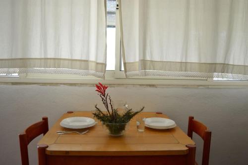 une table en bois avec deux assiettes et un vase de fleurs dans l'établissement Artist House, à Cardedu
