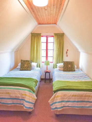two beds in a attic room with a window at Hill Billys Selfcatering in Winterton
