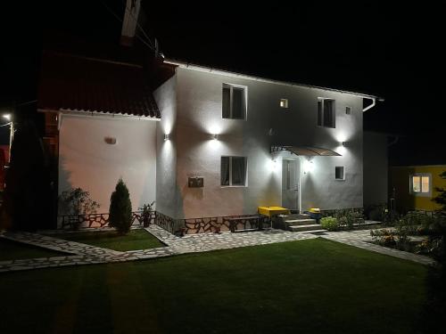 una gran casa blanca con un patio por la noche en Pensiunea Marydor, en Gârda de Sus