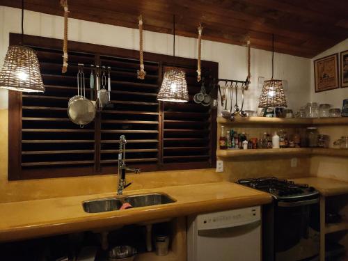 cocina con fregadero, fogones y luces colgantes en Casa Vermelha, en Pipa