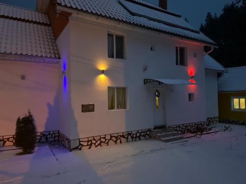 una casa blanca con luces azules y rojas. en Pensiunea Marydor, en Gârda de Sus