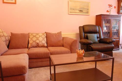 a living room with a couch and two chairs at Wulfrun in Tywyn