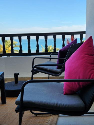 two chairs with pink pillows sitting on a balcony at L'univers de la mer appartement in Douar el Hafey