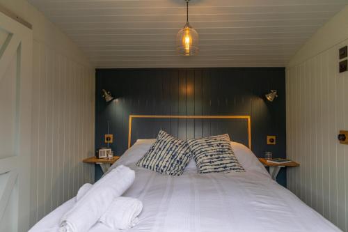 1 dormitorio con 1 cama con sábanas y almohadas blancas en Deer Lodge Shepherds Hut, en Rowlands Castle