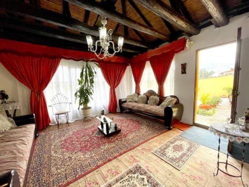 sala de estar con sofá y cortinas rojas en Great Rustic Colonial Villa in Punta Larga, Boyacá, en Nobsa