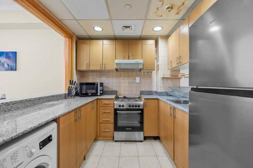 a kitchen with wooden cabinets and a stove top oven at Modern living nestled with 1BR_Silicon Oasis Dubai in Dubai