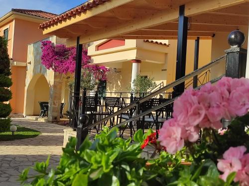 a patio with tables and chairs and pink flowers at Elanthi Village Apartments in Kalamaki