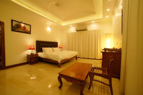 a bedroom with a bed and a table and a bench at TRAVANN in Alleppey