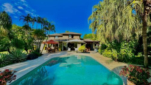 - une piscine en face d'une maison avec des palmiers dans l'établissement Villa Petit Tamarin : piscine bar et grand jardin tropical, à Tamarin