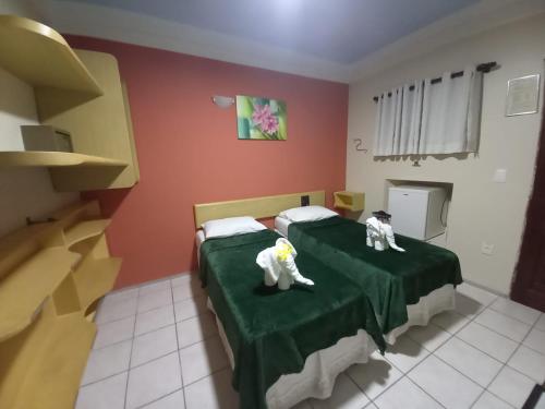 dois gatos de brinquedo sentados numa cama num quarto em Pousada Recifes de Corais em Porto de Galinhas