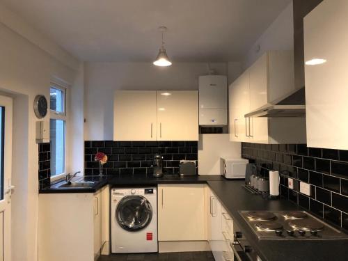 a kitchen with white cabinets and a washing machine at Comfortable Home From Home Bolton Central - Sleeps - 10 in Bolton