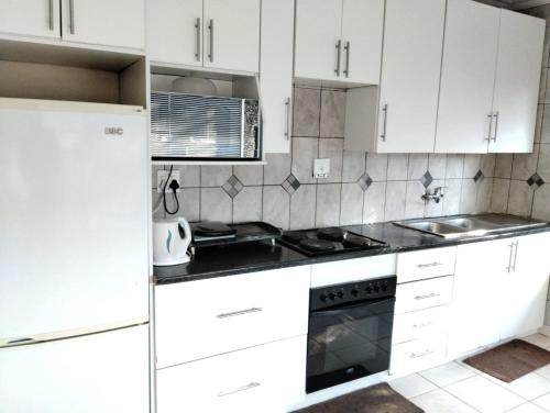 a kitchen with white cabinets and a stove top oven at Turquoise View Guesthouse in Middelburg