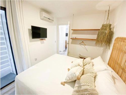 a bedroom with a white bed and a tv at m a r ė a in José Ignacio