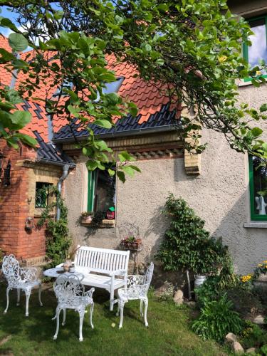 Raben Steinfeld的住宿－Little Cottage auf 2 Etagen，大楼前的白色长椅和椅子