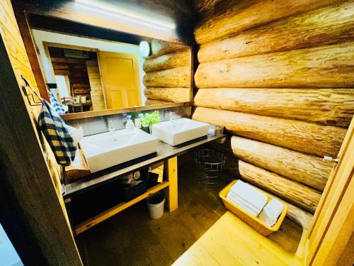 ein Badezimmer mit einem Waschbecken und einer Holzwand in der Unterkunft Yufuin Log House no Yado Tom Sawyer in Yufu