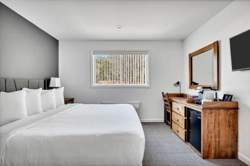 een hotelkamer met een groot bed en een televisie bij The Inn of Lake George in Lake George