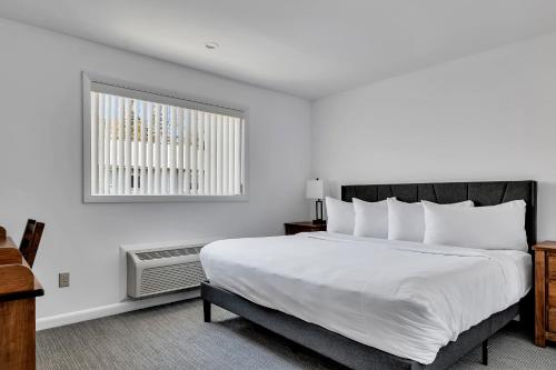 a bedroom with a large white bed and a window at The Inn of Lake George in Lake George