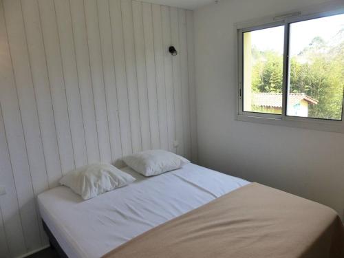 - un lit avec deux oreillers dans une chambre dotée d'une fenêtre dans l'établissement Residence AMARINE Appartement avec terrasse et piscine collective chauffée, à Capbreton