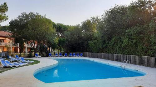 une piscine avec des chaises bleues et une clôture dans l'établissement Residence AMARINE Appartement avec terrasse et piscine collective chauffée, à Capbreton