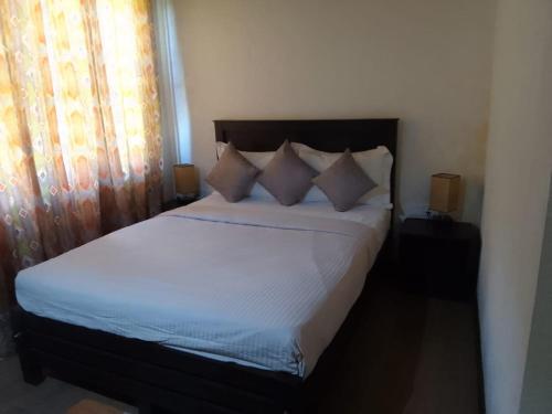 um quarto com uma cama com almofadas e uma janela em Nothern Residence em Jaffna