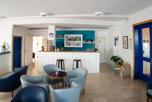 Cette chambre comprend un bar avec des chaises bleues et un comptoir. dans l'établissement Hotel Eugenio, à Cesenatico