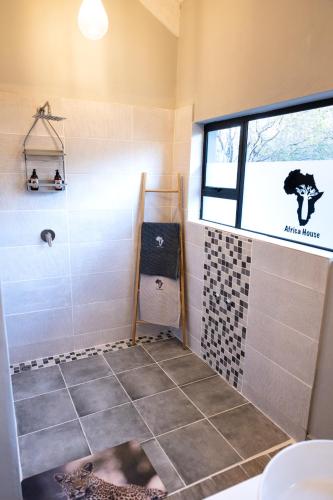 a bathroom with a shower with a window at Africa House in Hoedspruit