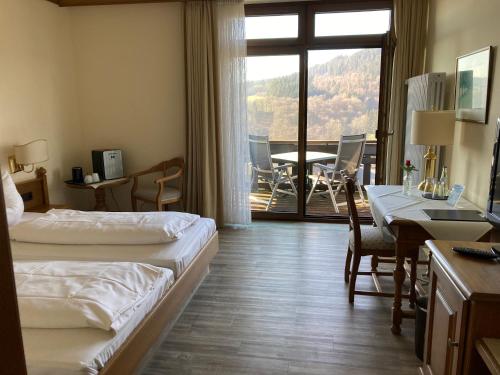 een hotelkamer met 2 bedden, een bureau en een tafel bij Landhaus Müllenborn in Gerolstein