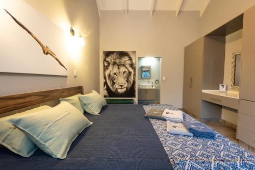 a bedroom with a bed with a lion painting on the wall at Africa House in Hoedspruit