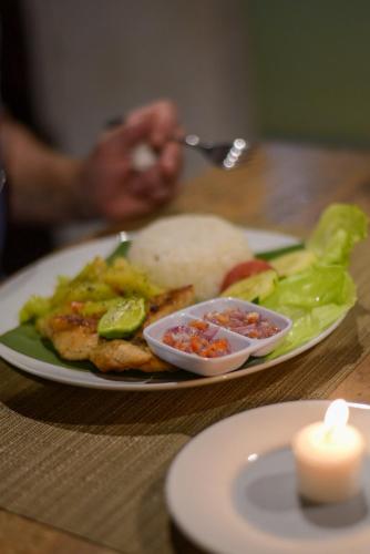a plate of food with a sandwich and a candle at Mesari Hut Lembongan in Nusa Lembongan