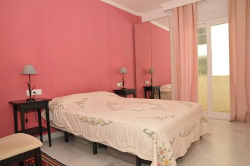 um quarto com uma cama e uma parede rosa em Estepona (in het hartje van het stadje) em Estepona