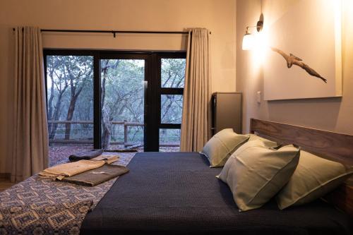 a bedroom with a large bed with a large window at Africa House in Hoedspruit