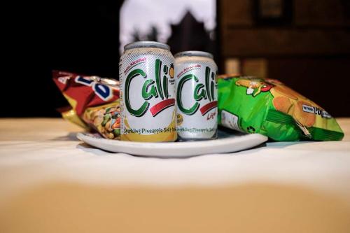 two cans of soda sitting on a plate with a bag of food at Loboc Nipa Huts Cottages Rental in Camisan