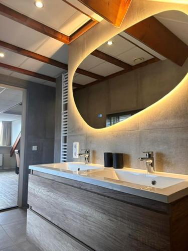 a bathroom with two sinks and a large mirror at Koetsementen appartementen met strandcabine in Domburg