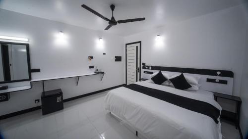 a bedroom with a bed and a ceiling fan at Sunset Beach Stay at Mathiveri in Mathiveri