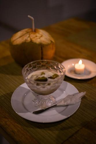 a bowl of food on a plate next to a candle at Mesari Hut Lembongan in Nusa Lembongan