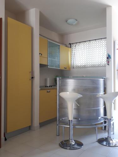 una cucina con armadi gialli e 2 sgabelli bianchi di Apartment Finn a Rovigno (Rovinj)