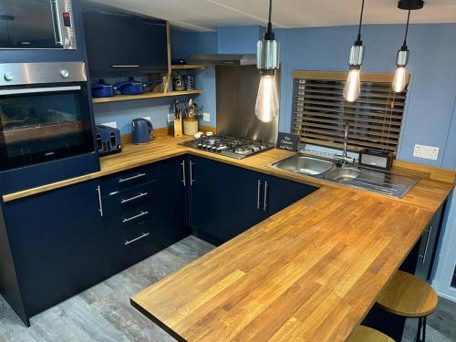 a kitchen with blue cabinets and a wooden counter top at 2 bedroom lodge - The Cherries (24) Caer beris holiday park in Builth Wells