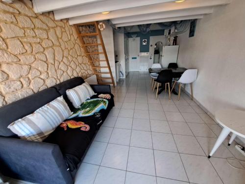 un salon avec un canapé et un mur en pierre dans l'établissement Studio Mezzanine pour 4 à Marseillan avec Parking Privé, TV et Cuisine Équipée - FR-1-326-783, à Marseillan
