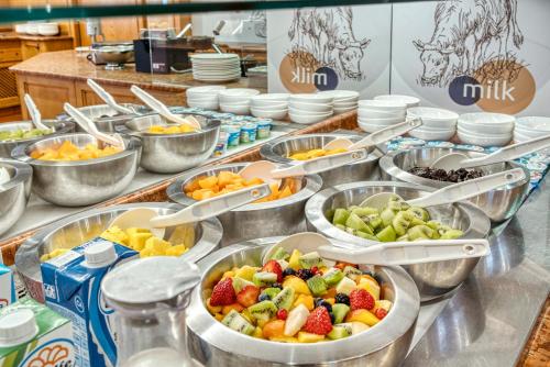 a buffet filled with bowls of fruit and vegetables at Alpenresort Belvedere in Molveno