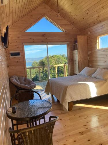 a bedroom with a bed and a table and chairs at Lodge Güitimó in Ancud