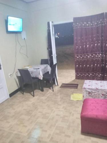 ein Wohnzimmer mit einem Tisch, Stühlen und einem TV in der Unterkunft Kapowlito Real Estate Casa Grootblijdenshoopweg in Paramaribo