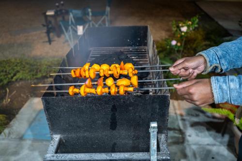 a person cooking a bunch of hot dogs on a grill at SaffronStays Wood Sparrow in Bhīm Tāl