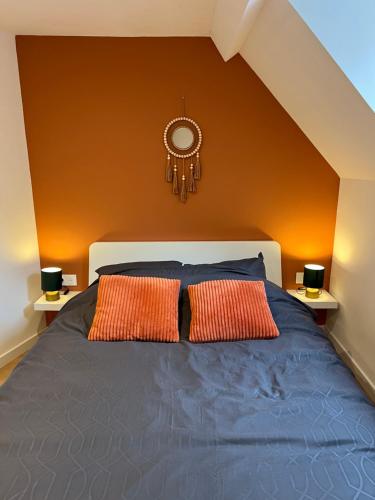 a bedroom with a bed with two orange pillows at Maison Bohème in Hénin-Beaumont