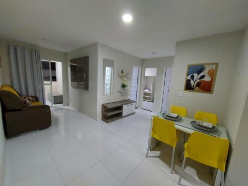 ein Wohnzimmer mit einem Tisch und gelben Stühlen in der Unterkunft Residencial Atalaia Sul in Aracaju